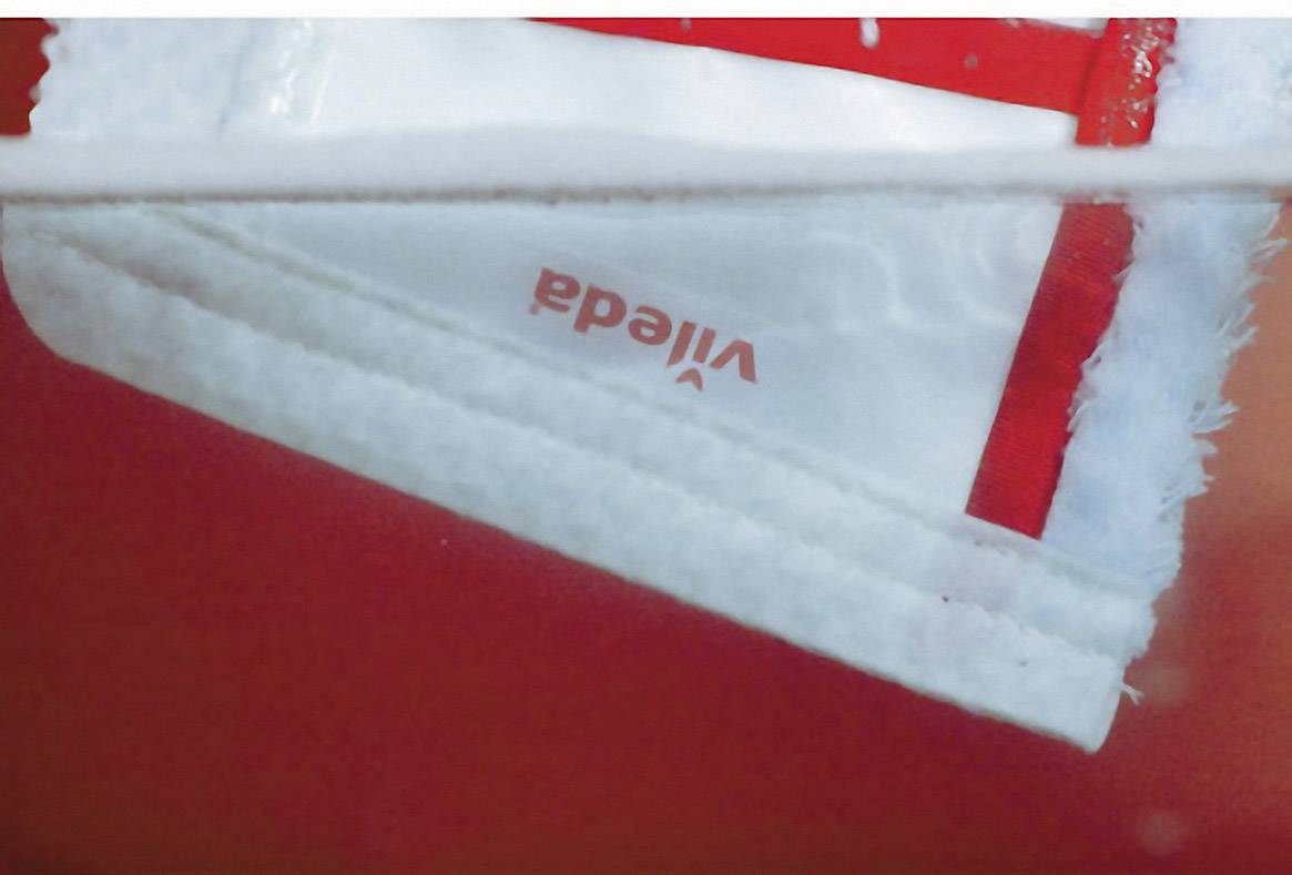 Un balai à franges Vileda rouge et blanc est trempé dans l'eau.