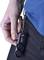 Une main tient un porte-clés noir X-LIFE, attaché à une ceinture.