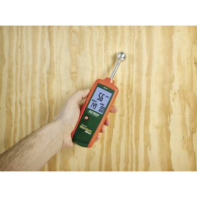 Un humidimètre indique 5,6 % d'humidité sur une surface en bois, tenu dans une main.