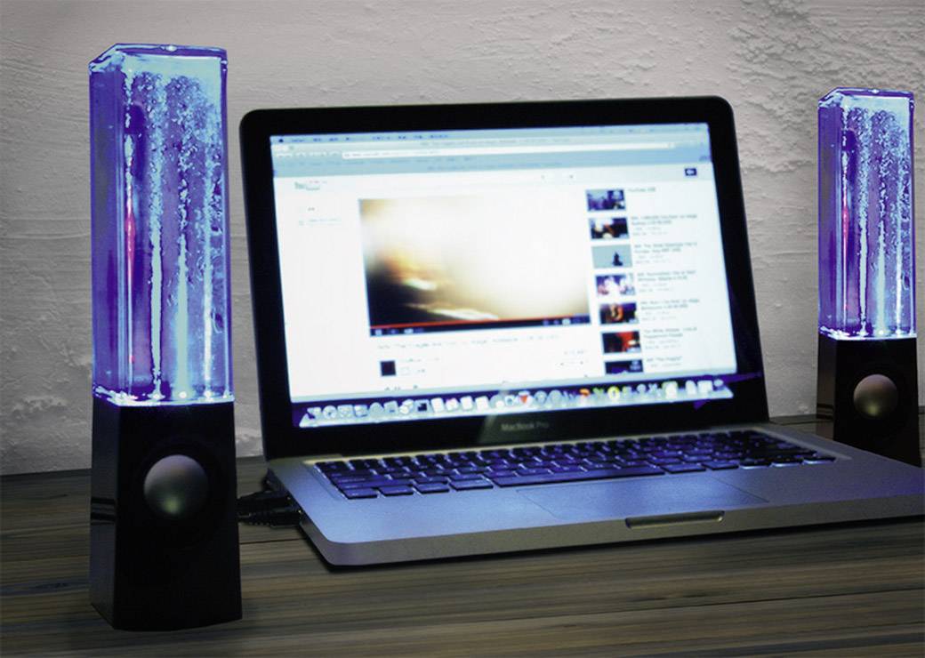 Un ordinateur portable affiche une vidéo, flanqué de deux enceintes à éclairage bleu avec des colonnes d'eau à l'intérieur.