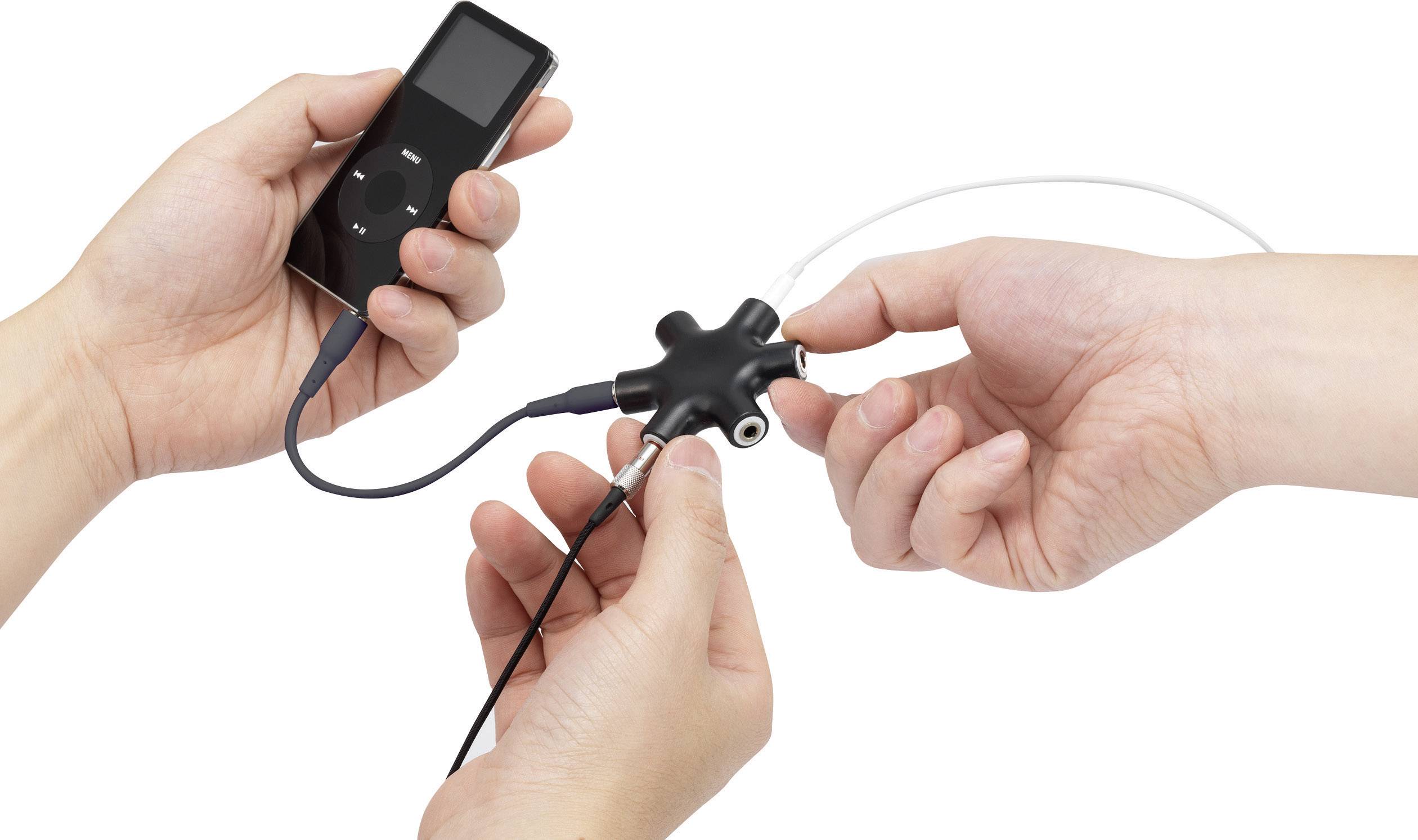Deux mains tiennent un lecteur de musique portable et un adaptateur de partage de son reliés l'un à l'autre.