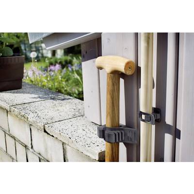 La canne et la canne de marche sont fixées contre le mur de la maison dans un support en plastique.