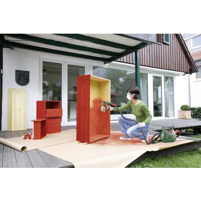 Une personne pulvérise de la peinture rouge sur une étagère en bois à l'aide d'un pistolet de pulvérisation sur une terrasse. D'autres meubles peints sont visibles en arrière-plan.