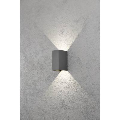 Lampe murale moderne illuminant doucement un mur en béton. La lumière rayonne uniformément vers le haut et vers le bas, créant un motif élégant.
