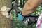 Une personne portant des gants écorce un arbre avec une hache dans une forêt. Le focus est mis sur la hache et l'arbre, avec un environnement verdoyant et boisé.