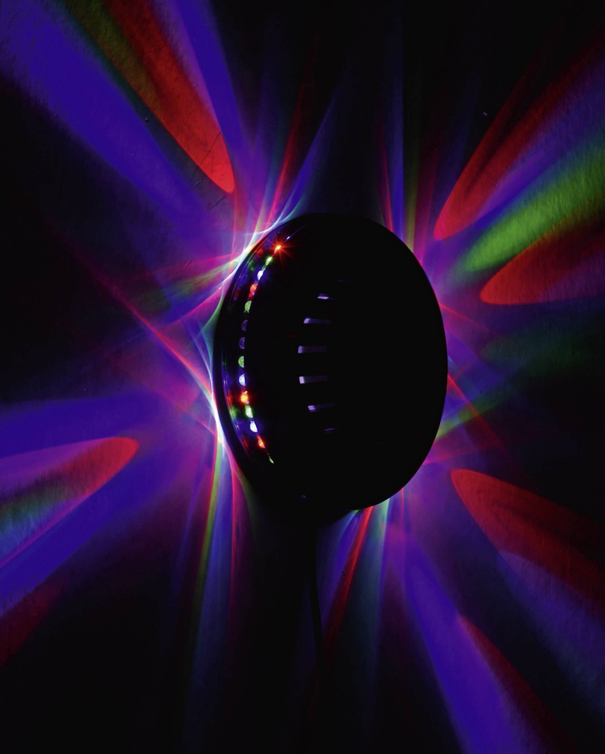 Un objet noir et ovale sur un mur projette des rayons lumineux colorés en rouge et bleu, se propageant radialement vers l'extérieur.