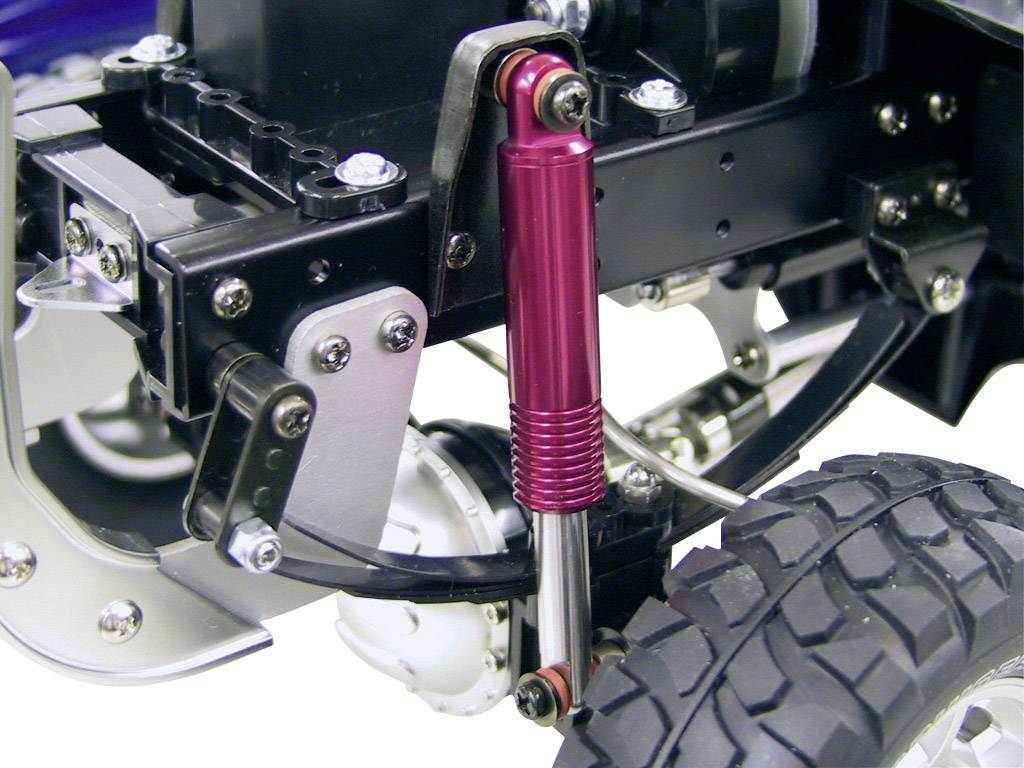 Un gros plan détaillé sur l'amortisseur rouge d'une voiture miniature, fixé sur un support métallique noir.