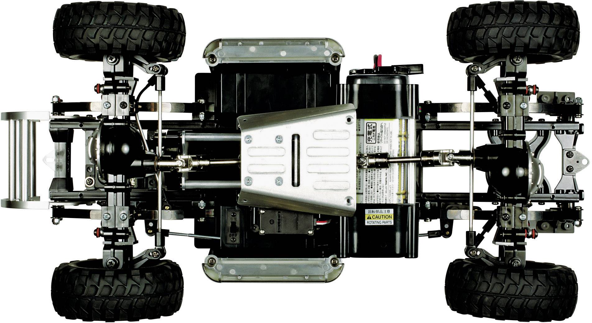 Vue du châssis d'une voiture télécommandée avec suspension et transmission détaillées. Des pneus tout-terrain sont visibles.