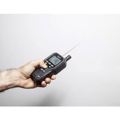 Une main tient un télémètre laser pointé vers un mur. L'écran affiche une mesure de '129'.
