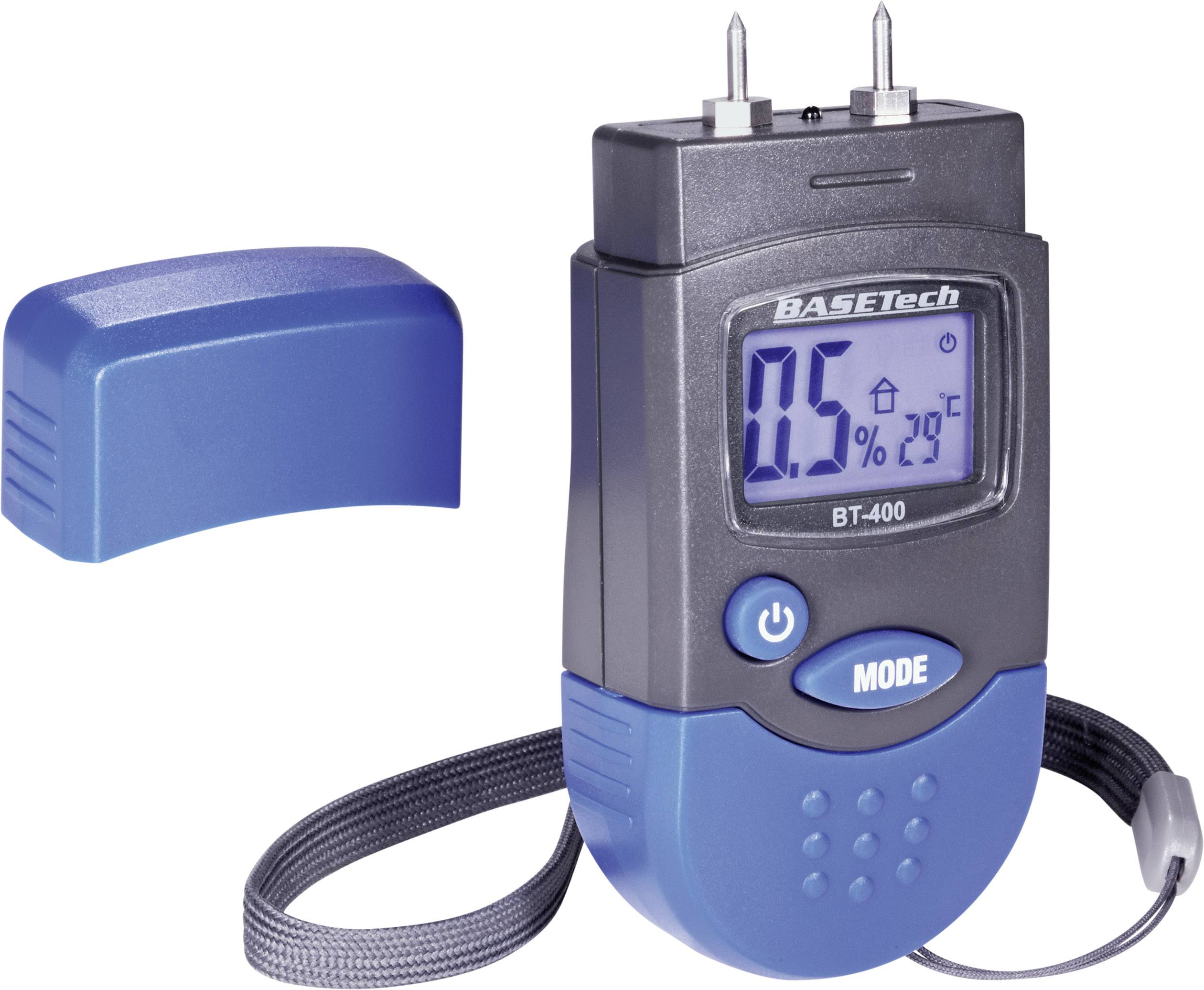 Appareil de mesure d'humidité avec affichage LCD, indiquant '0,5%' et '29°C', deux broches de mesure en haut. Couvercle bleu et lanière de transport visibles.