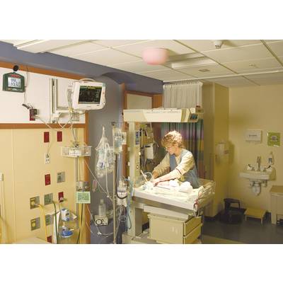 Une infirmière prend soin d'un nouveau-né dans une chambre d'hôpital équipée d'appareils médicaux.