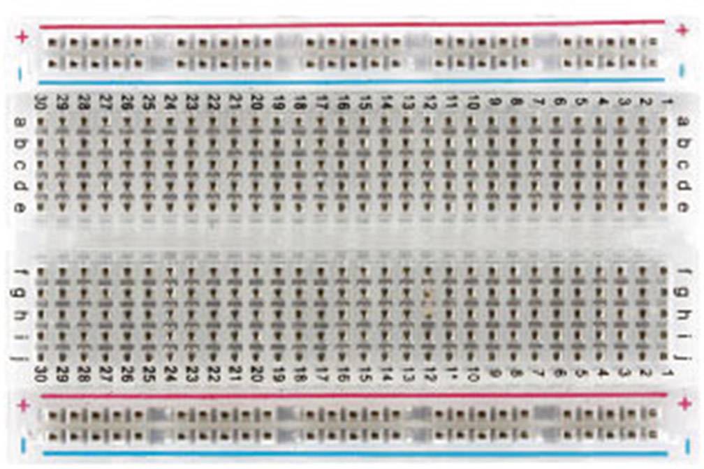 Une platine d'expérimentation avec 30 rangées horizontales de contacts, avec deux rails d'alimentation verticaux en rouge et bleu en haut et en bas.