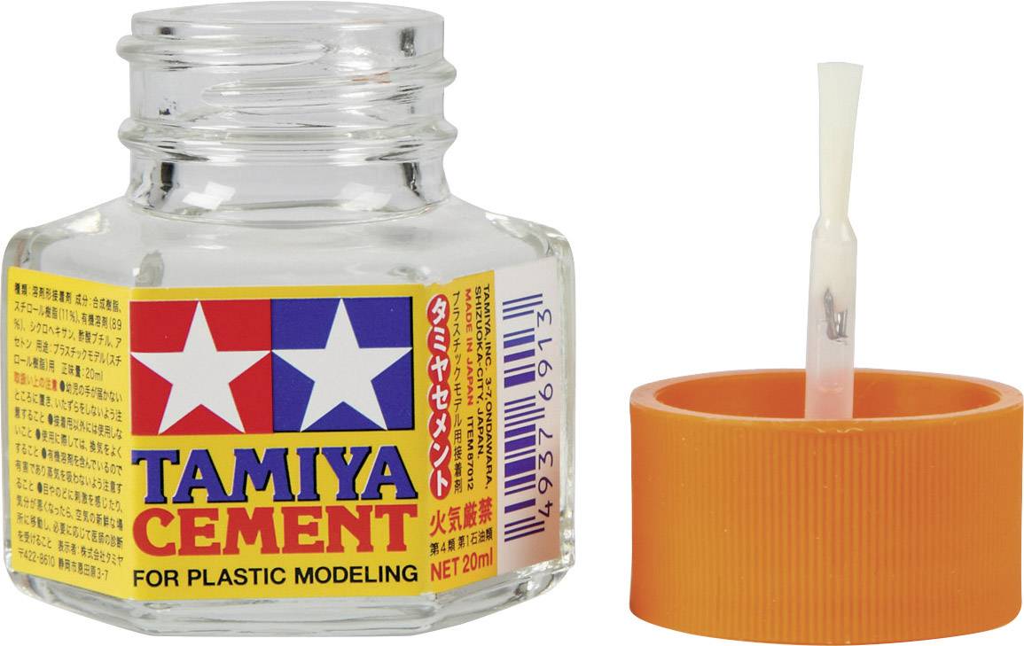 Bouteille en verre de colle pour maquettes en plastique, avec l'étiquette 'TAMIYA CEMENT', à côté du bouchon orange muni d'un pinceau.