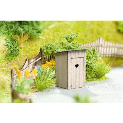 Une maquette de jardin présente un petit cabanon de toilettes en bois avec une découpe en forme de cœur, entouré de plantes et d'une clôture.