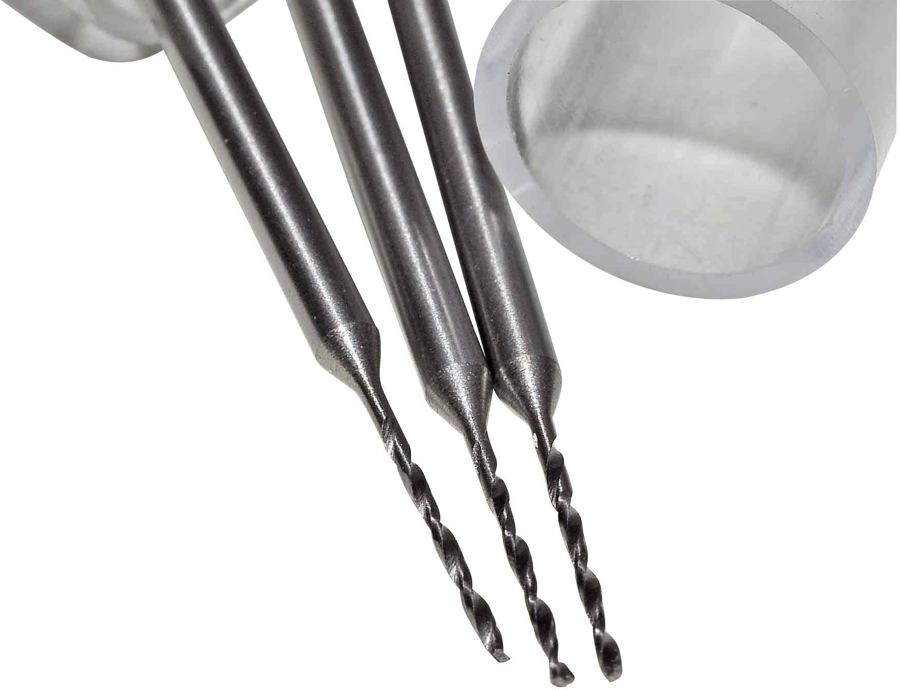 Trois petites perceuses à pointe fine, placées côte à côte devant un cylindre transparent, sur une surface gris clair.