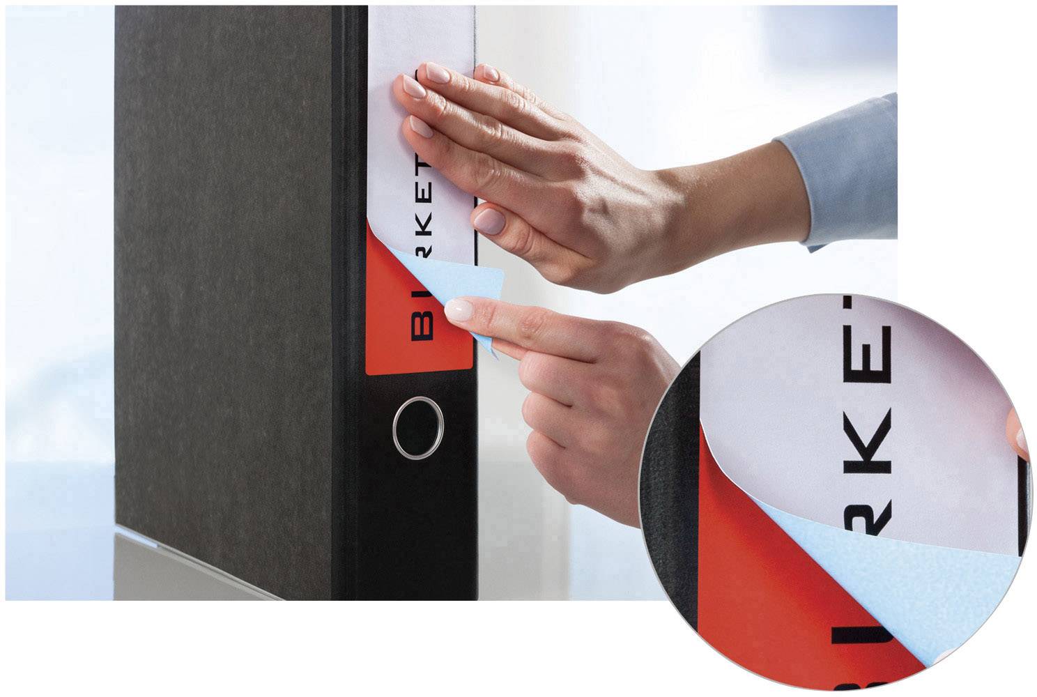 Une personne colle une nouvelle étiquette sur un classeur noir. Un agrandissement montre la structure amovible de l'étiquette.