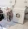 Machine à laver et étendoir à linge avec des serviettes colorées sur un sol carrelé dans une buanderie.