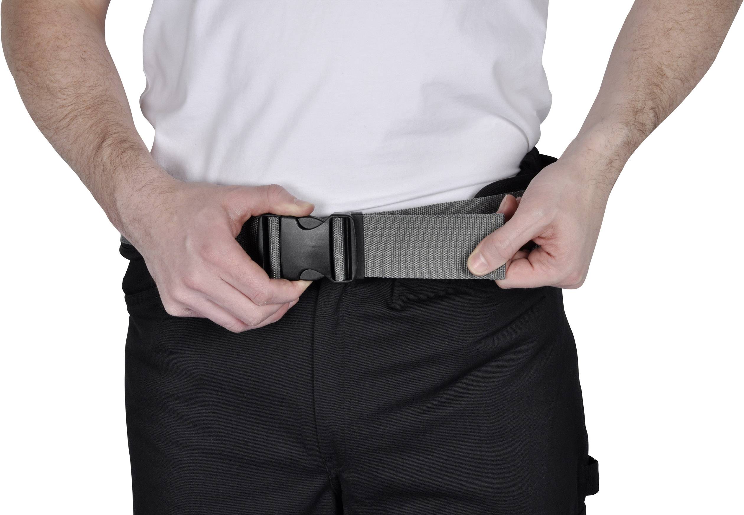 Une personne attache une ceinture grise avec une boucle en plastique noir autour de son pantalon noir.