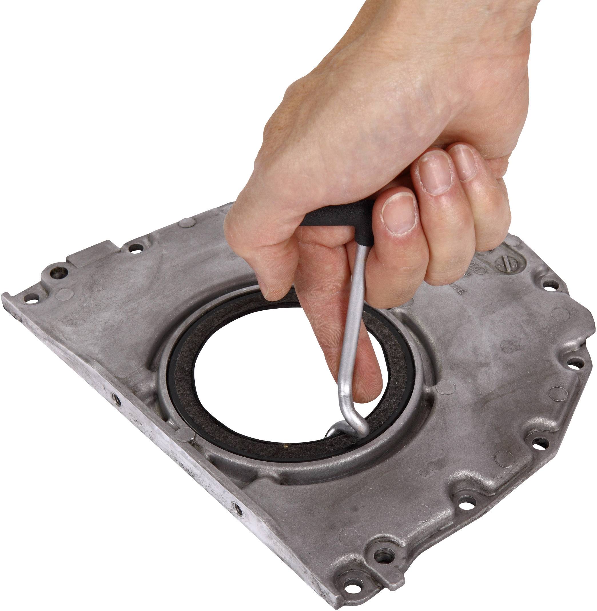 Une main tient un outil pour retirer un joint d'étanchéité d'une plaque métallique.