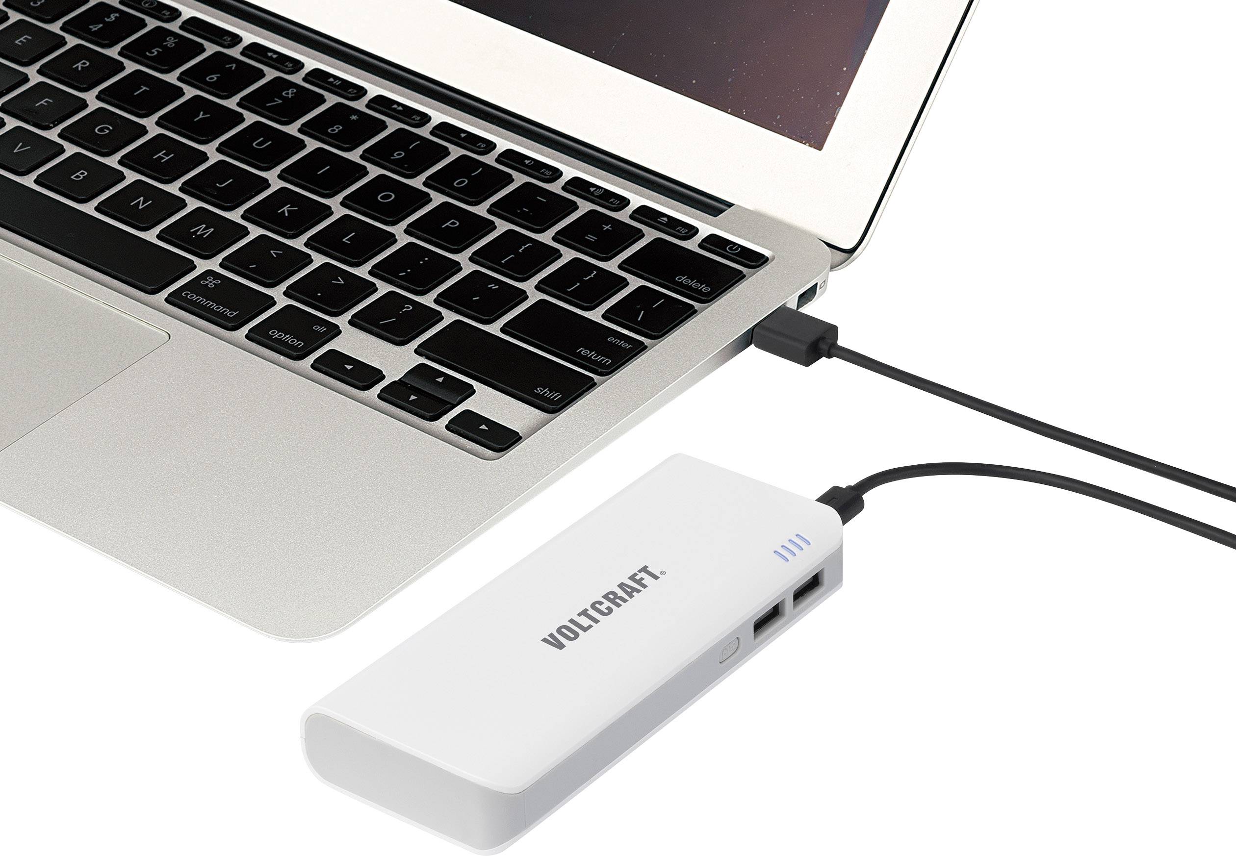 Un ordinateur portable est connecté via un câble USB à une batterie externe blanche qui repose sur une surface plane.