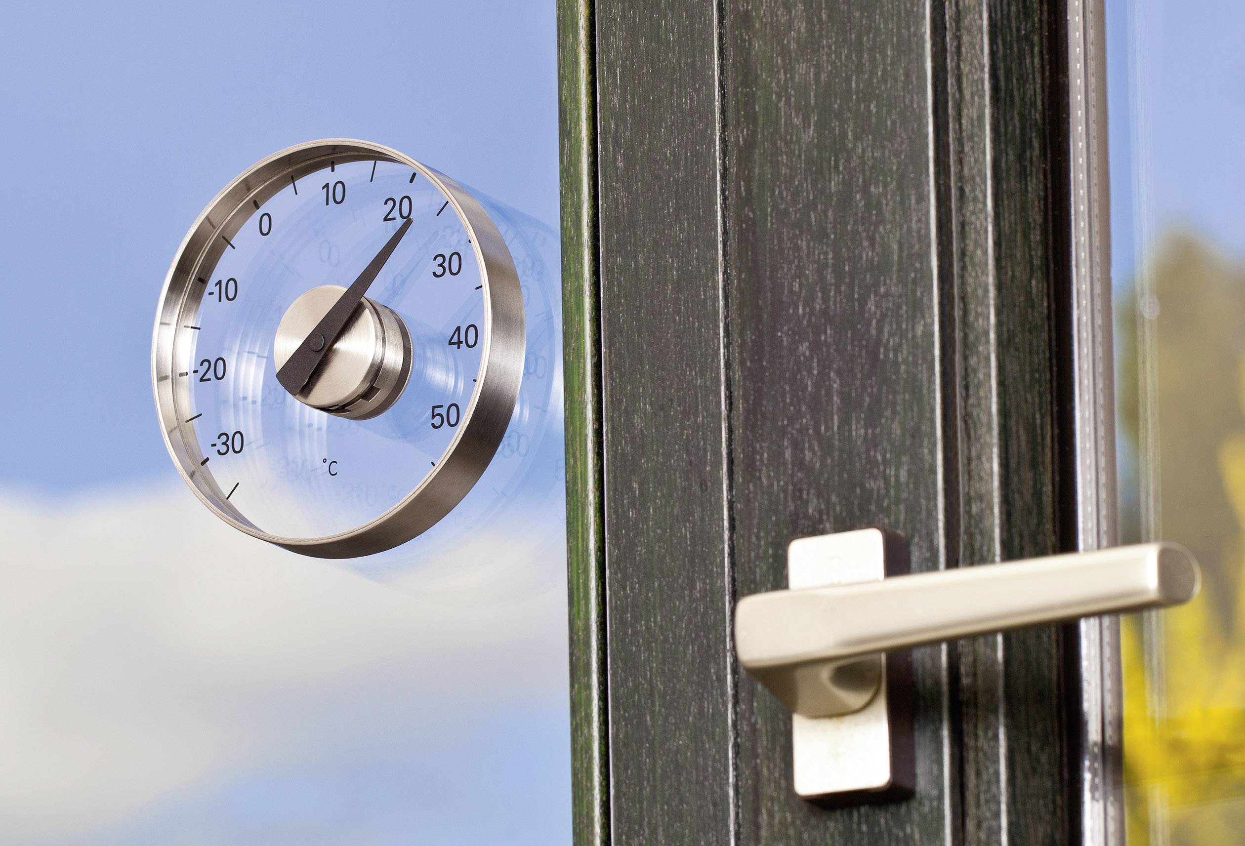 Le thermomètre extérieur indique environ 20 degrés Celsius. En dessous, une poignée de fenêtre blanche est intégrée dans une fenêtre fermée.