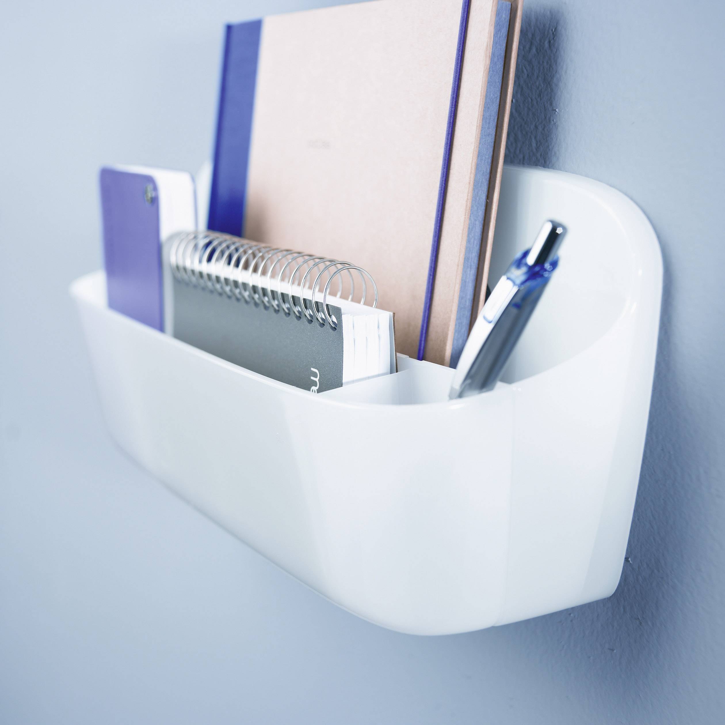 Organisateur mural avec un carnet de notes, un classeur à anneaux, un cahier et un stylo à bille.