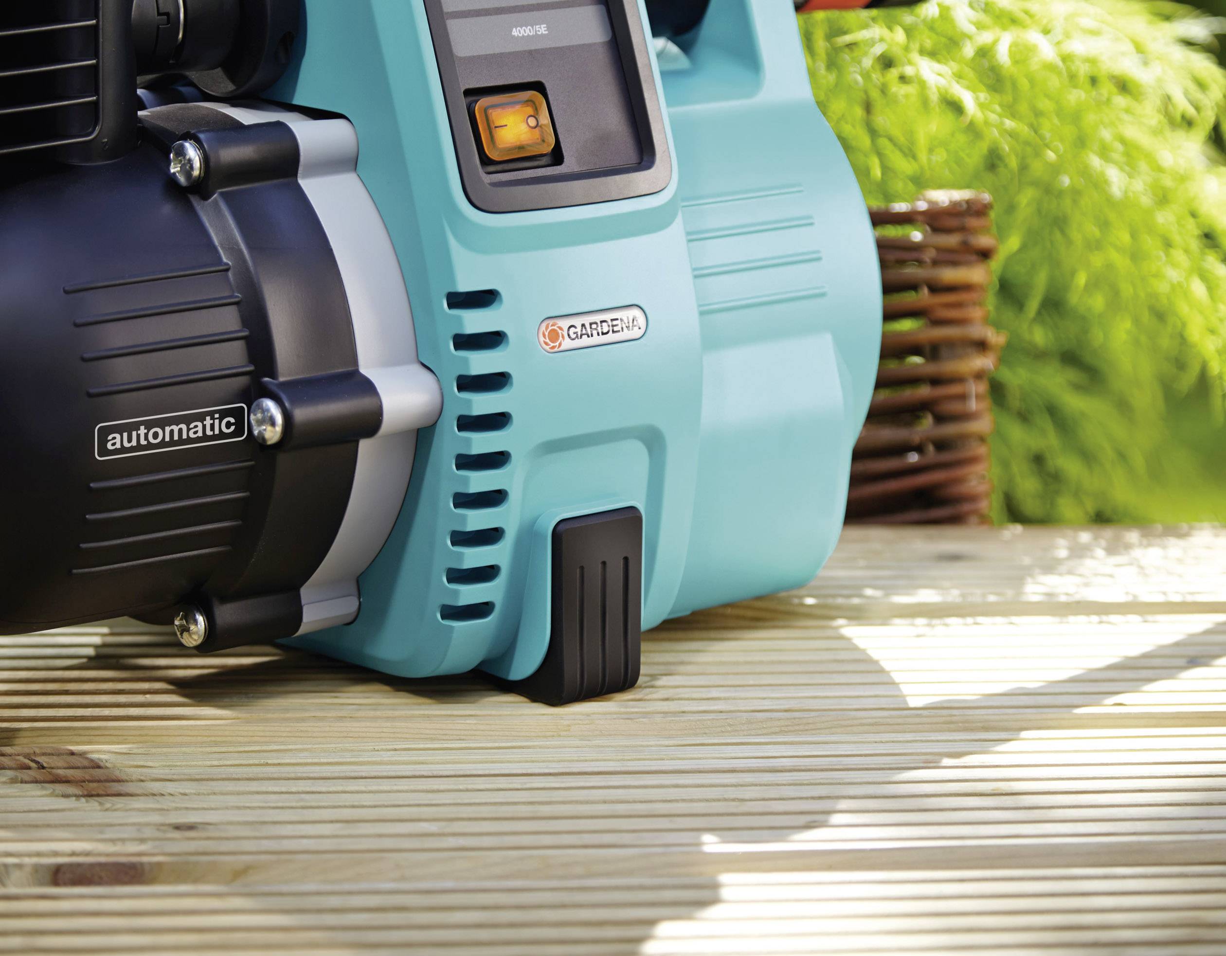 Pompe de jardin sur une terrasse en bois à côté de feuillage vert, avec la marque et l'inscription « automatic » bien visibles.