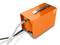 Appareil orange avec une poignée et des connexions, probablement une pompe ou un filtre. Un tuyau transparent en sort.