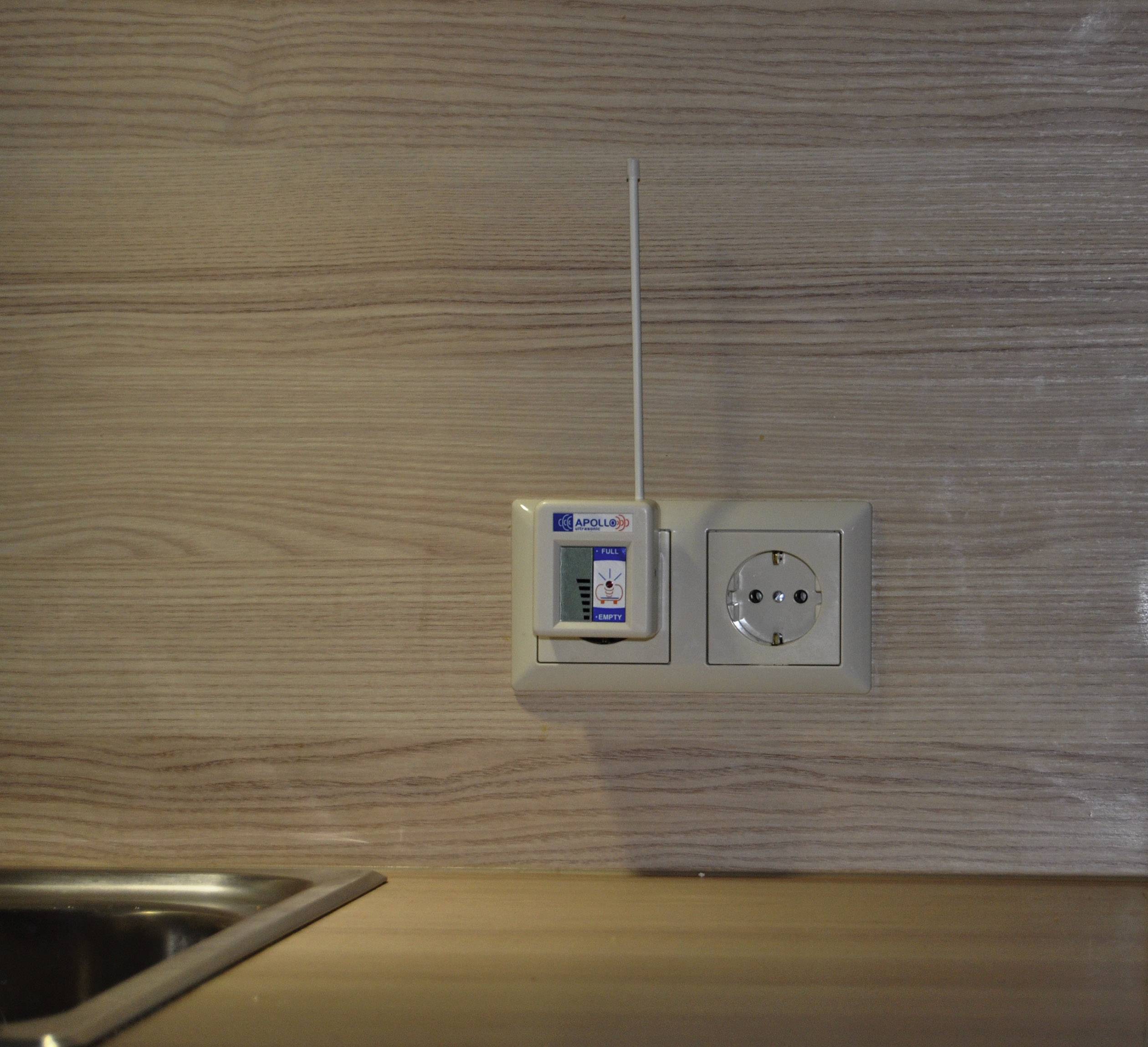 Prise électrique avec un appareil WiFi sur un mur en bois, à côté d'un évier.