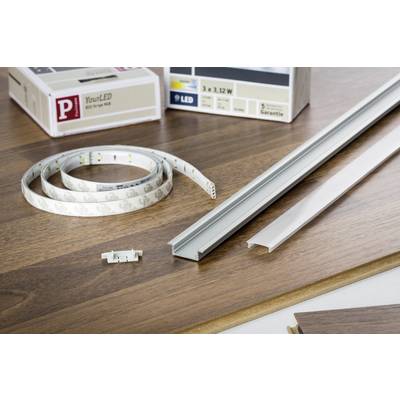 Bande lumineuse LED et accessoires sur une table en bois. On peut voir un ruban LED, un profilé en aluminium et un bornier de connexion.