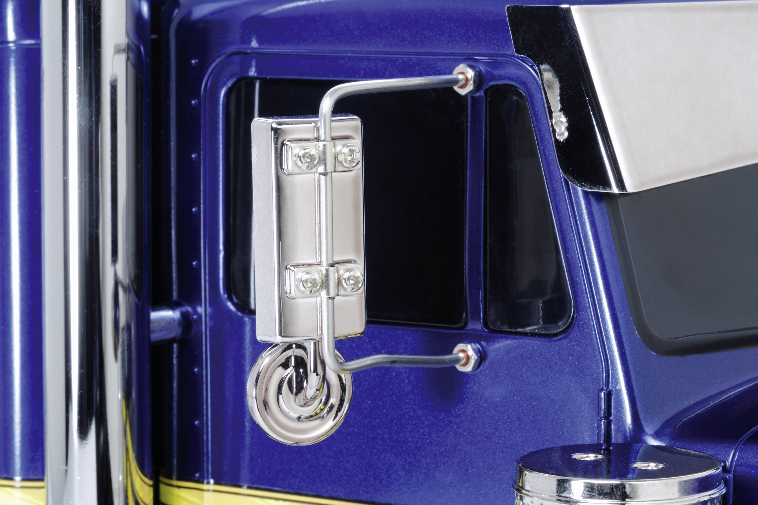 Gros plan sur un camion bleu avec des détails argentés, incluant un grand rétroviseur sur la portière.