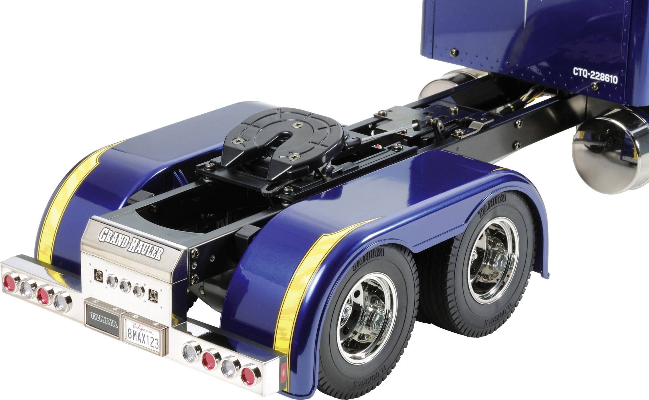 Camion-remorque de jouet bleu à deux essieux avec des détails jaunes. Vue arrière montrant les roues, les feux et la plaque d'immatriculation.