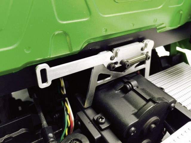 Un véhicule modèle vert avec un moteur et des composants de transmission visibles en gros plan. Des détails mécaniques et des câbles sont clairement identifiables.