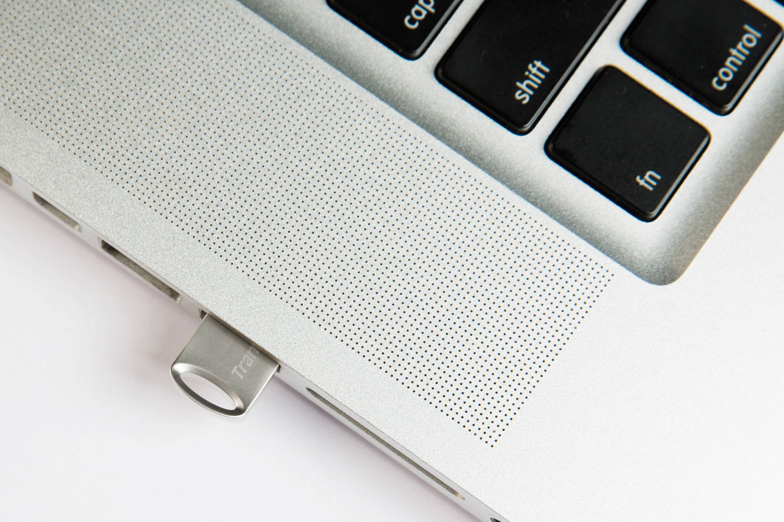 Un gros plan d'un ordinateur portable avec une clé USB branchée sur une surface claire.