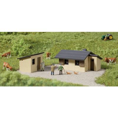 Petit diorama d'une ferme miniature avec deux bâtiments, des personnages, deux chiens et des vaches sur un champ vert. Un tracteur est visible en arrière-plan.