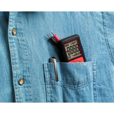 Un multimètre est glissé dans la poche de poitrine d'une chemise bleue. Il affiche '8888' sur son écran. Un stylo est posé à côté.