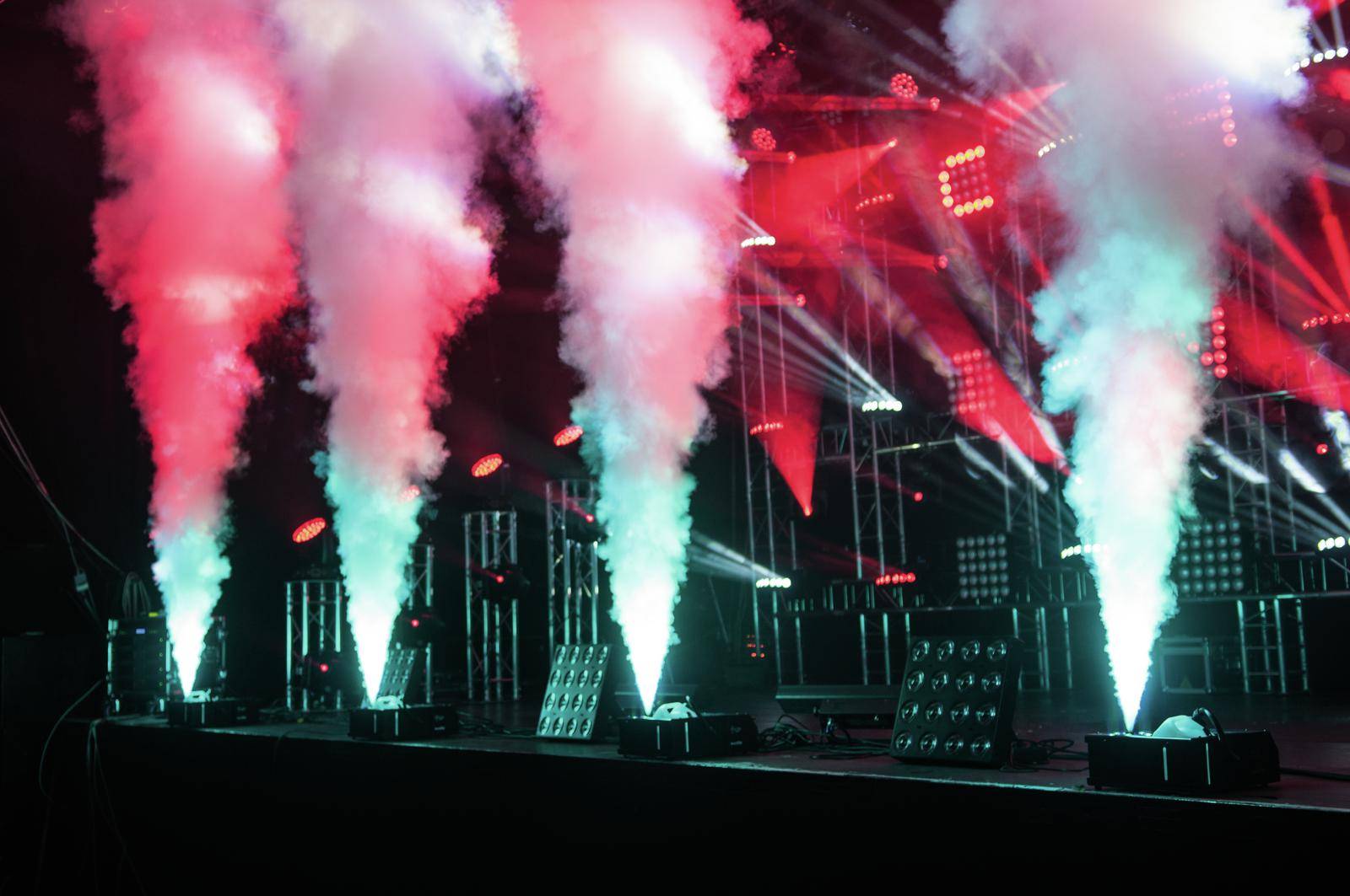 Une scène avec un spectacle lumineux coloré et de la brume s'élevant de plusieurs machines crée une atmosphère dynamique et palpitante.