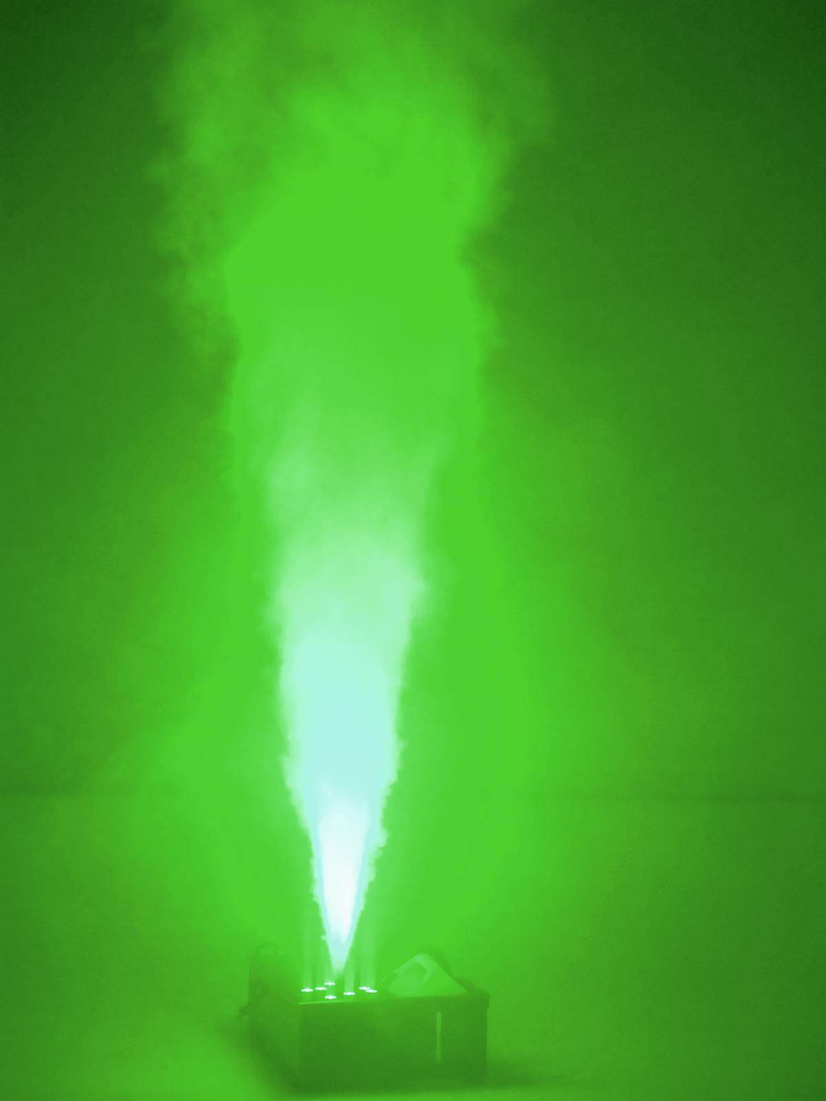 Un jet de fumée verte s'élève d'une petite machine posée au sol. La scène est baignée d'une lueur verte intense.
