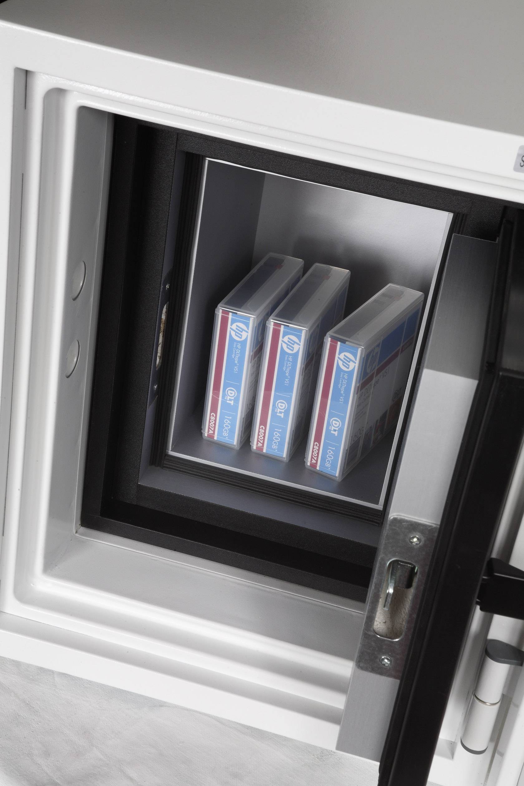Un coffre-fort ouvert montre trois boîtes de supports de données stockés en toute sécurité. Le coffre-fort transmet une impression de protection et de sécurité.