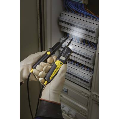 Un électricien portant des gants de protection utilise un multimètre numérique pour vérifier l'électricité dans un armoire électrique ouverte.