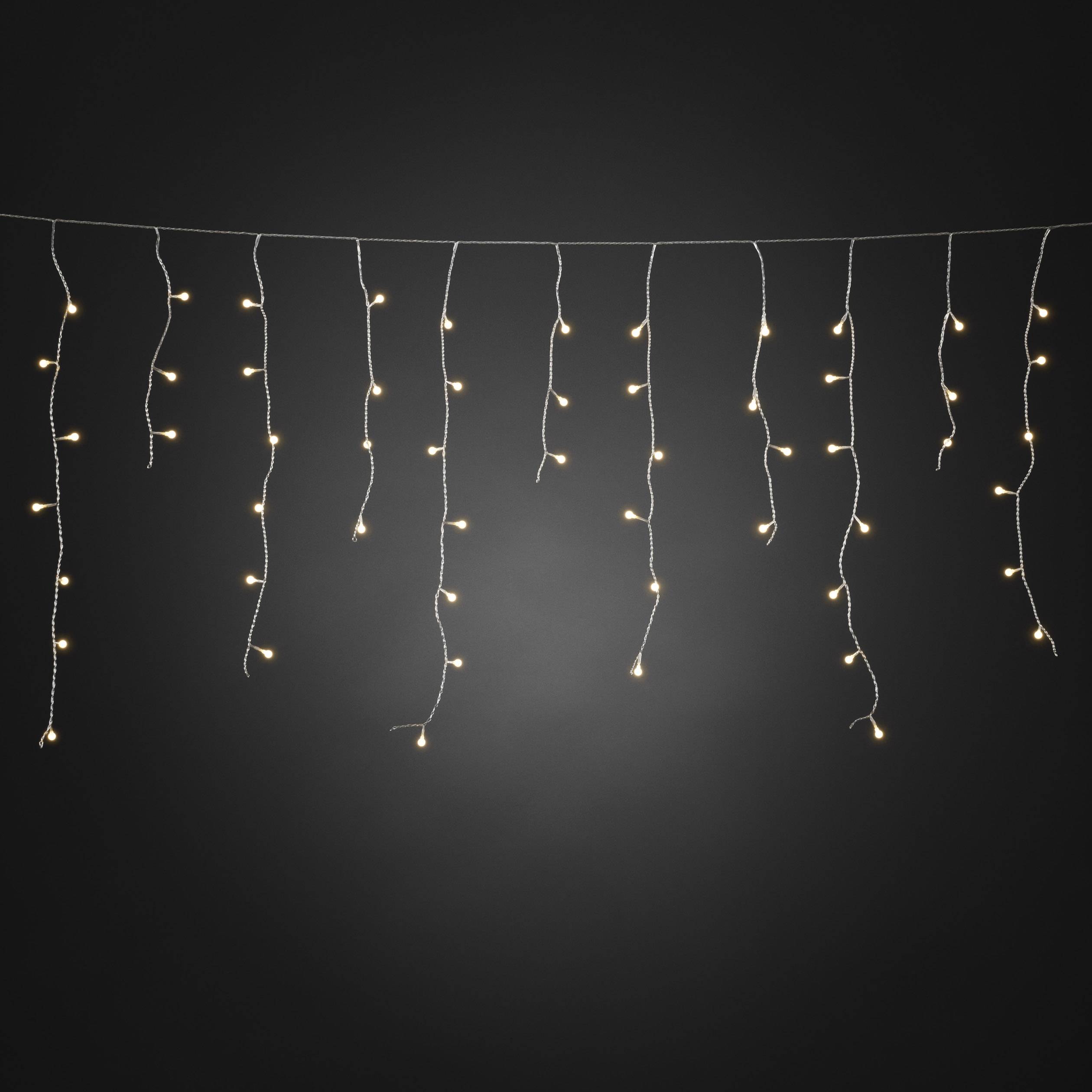 Une guirlande lumineuse avec de petites lumières blanc chaud est suspendue horizontalement devant un fond sombre.