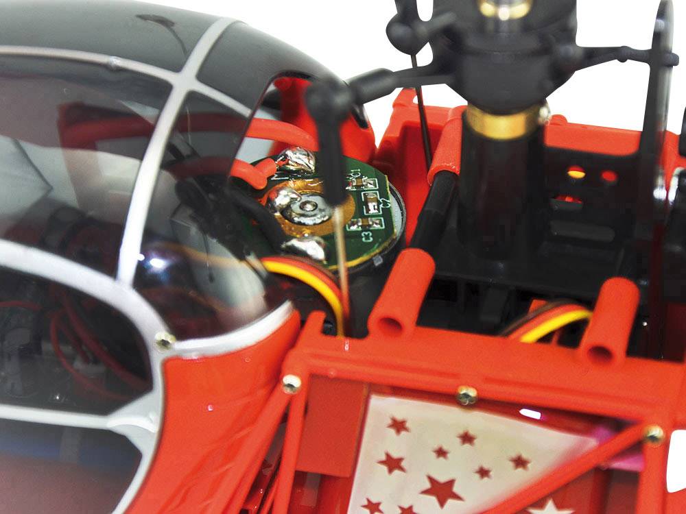 Modèle rouge d'un hélicoptère à cabine ouverte, montrant les composants électroniques et le câblage intérieur.