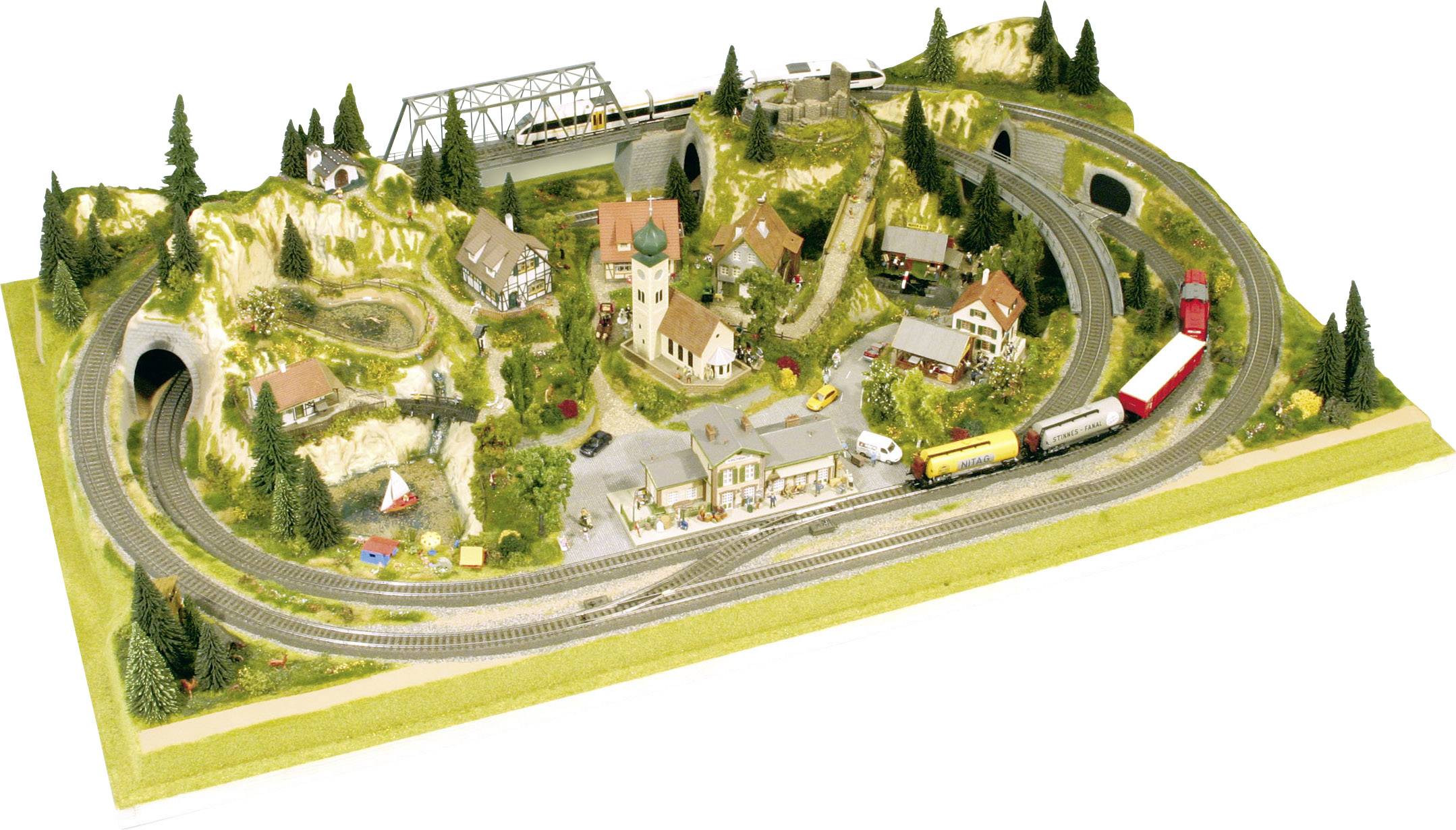 Un réseau de trains miniatures représente un paysage avec des collines, des ponts, des maisons et des tunnels. Plusieurs trains circulent sur les voies.