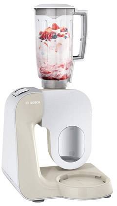 Un mixeur blanc, rempli de lait et de baies, est posé sur une table. L'appareil est prêt à préparer des smoothies ou des milkshakes.