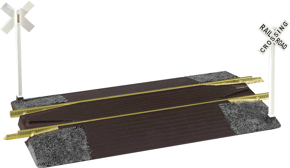 Passage à niveau de train miniature avec barrières et panneaux de signalisation des deux côtés, représentant une simulation d'un scénario réel de croisement routier.