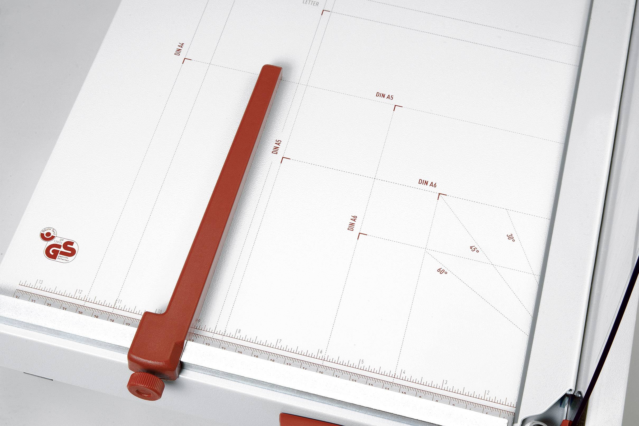 Une table à dessin avec une règle rouge, graduée pour les formats DIN. Elle présente des mesures et des lignes pour un positionnement précis du papier.