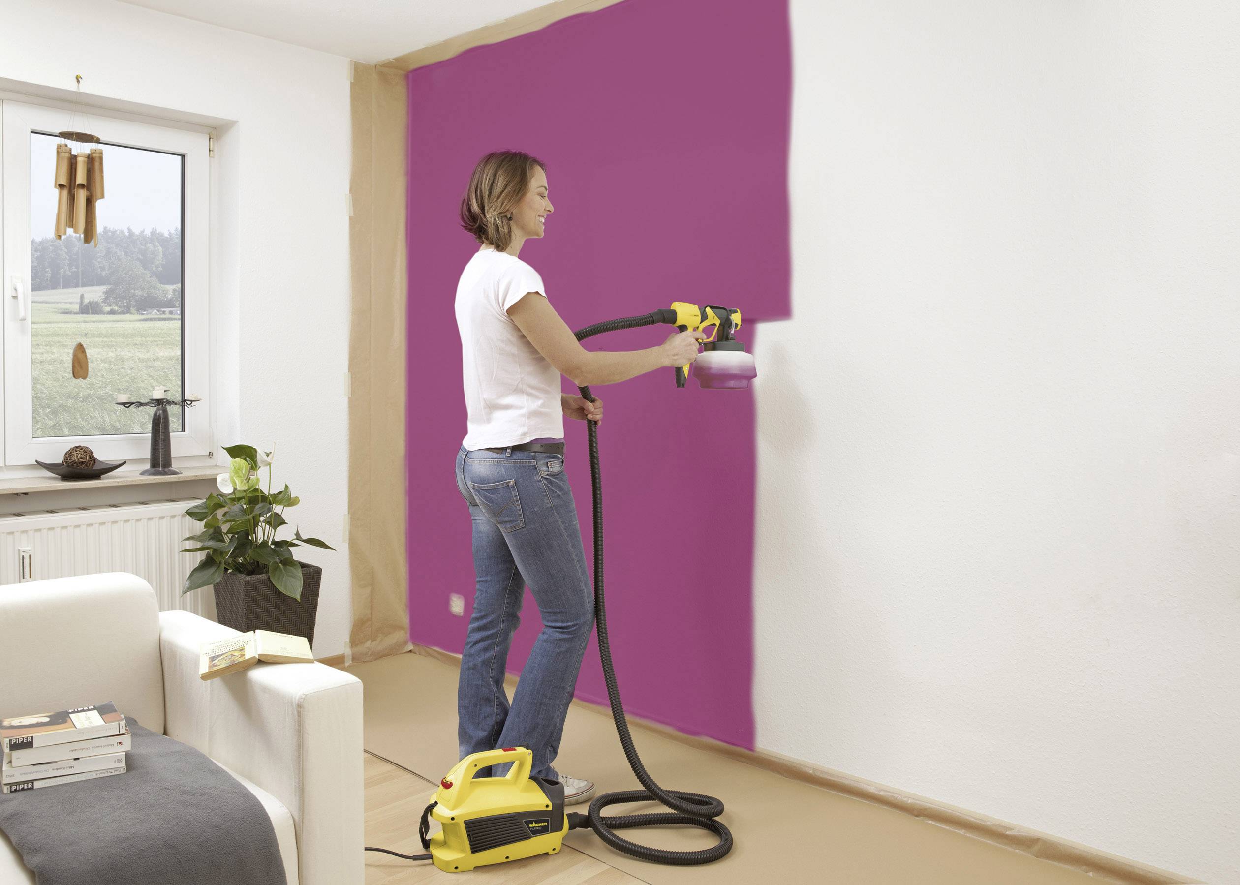 Une femme utilise un pistolet de peinture pour peindre un mur blanc en rose. Une fenêtre avec une vue sur un paysage est visible en arrière-plan.