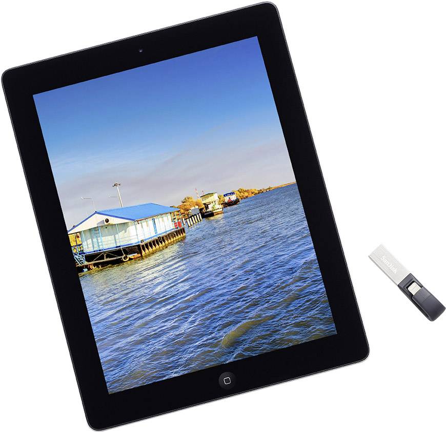 Une tablette affiche une photo de maisons flottantes sur un plan d'eau calme sous un ciel bleu. À côté se trouve une petite clé USB.
