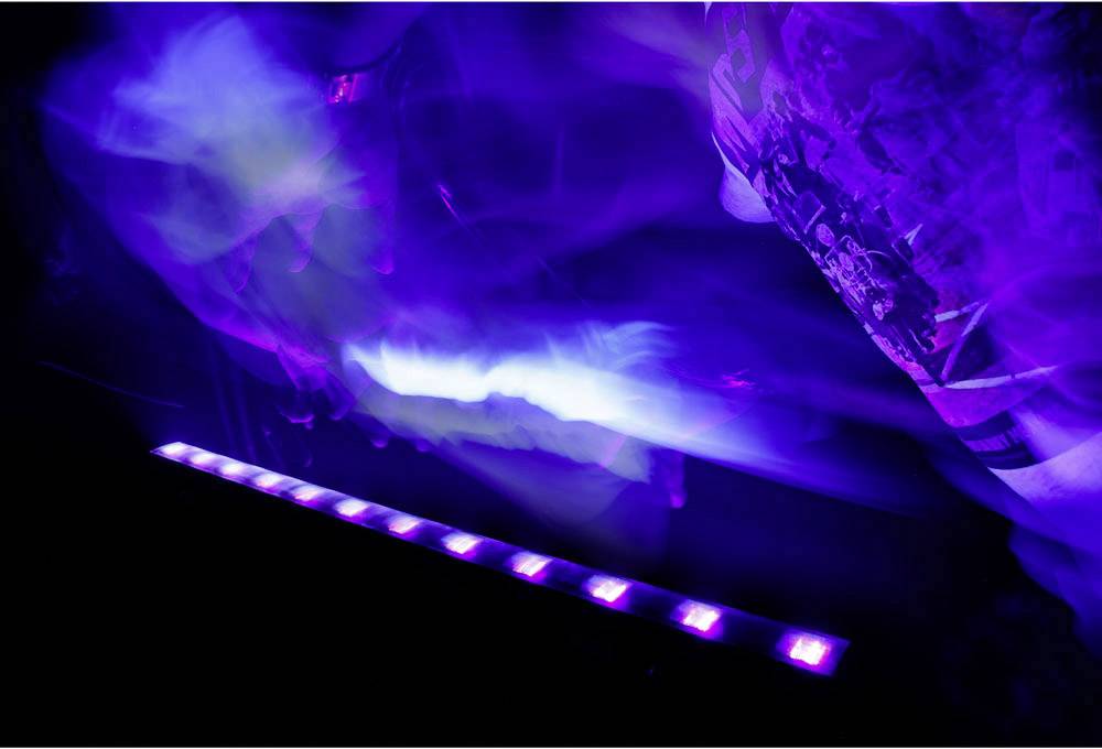 Des lumières colorées et des formes floues dans un environnement sombre suggèrent une scène dynamique et animée, probablement lors d'un événement.