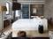 Chambre d'hôtel moderne avec un lit double central, téléviseur à écran plat au mur, et une salle de bain ouverte.